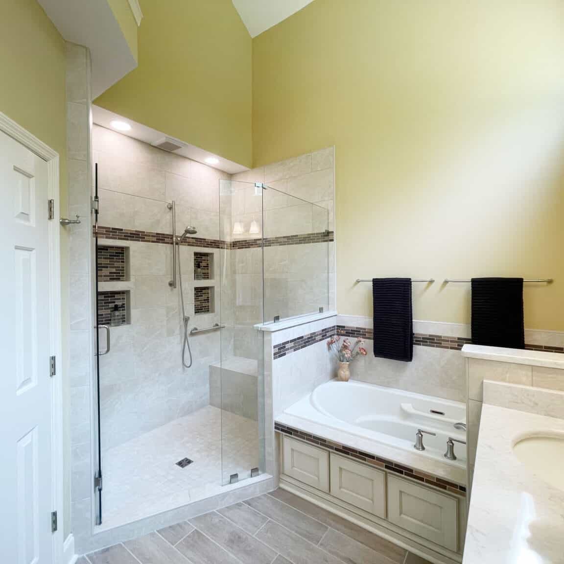 bathroom remodel with angled shower opening and tub with grab bars